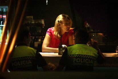 Esta es una de las imágenes que tomó el fotógrafo, en la que se aprecia a los dos agentes que le requisaron la cámara realizando una consumición en la barra de un bar. En ese momento, el coche policial estaba aparcado con las luces de emergencia encendidas.