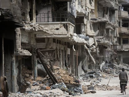 Un hombre monta en bicicleta entre las ruinas de la golpeada Homs.