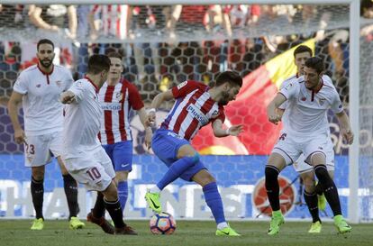 El centrocampista belga del Atlético de Madrid Jannick Ferreira-Carrasco con el balón ante los jugadores del Sevilla, Sergio Escudero y Samir Nasri.