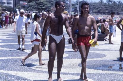 Dos hombres pasean por la avenida Atlántica de la playa de Copacabana, uno de los lugares favoritos de encuentro de los cariocas. Su pavimento, obra del paisajista Burle Marx, es una de los elementos más reconocibles de la ciudad y por su extensión, 4,5 kilómetros, está considerado como una de las mayores obras de arte urbano.