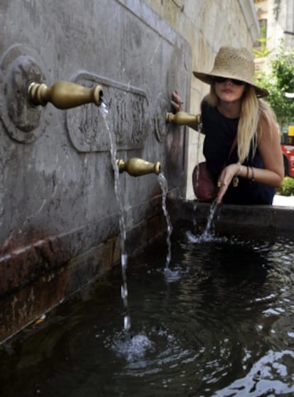Una mujer se refresca en una fuente del centro de Granada en plena ola de calor por la masa de aire africano.