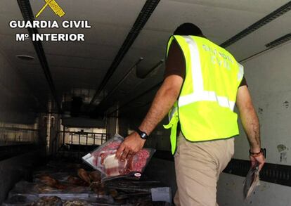 A Civil Guard officer inspects a truck containing expired ham.