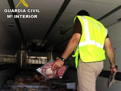 A Civil Guard officer inspects a truck containing expired ham.