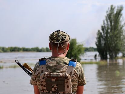 A Ukrainian soldier stands on a street flooded by the ruptured Nova Kakhovka dam in Kherson on May 6, 2023.