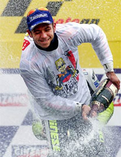 Rossi, vestido con la camiseta conmemorativa de su cuarto título, celebra con cava su victoria en Brasil.