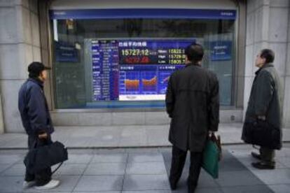 Varios viandantes observan una pantalla que muestra el valor alcanzado por el índice Nikkei al cierre de la sesión en la Bolsa de Tokio. EFE/Archivo
