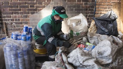 Una recicladora con mascarilla clasifica material reciclable en una nave de una asociación de recicladores de Bogotá.