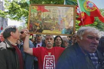 Un hombre muestra un póster con un dibujo que recuerda la Revolución de los Claveles durante uno de los homenajes del 40 aniversario de dicha revolución celebrado en la plaza de Carmo en Lisboa (Portugal) hoy.