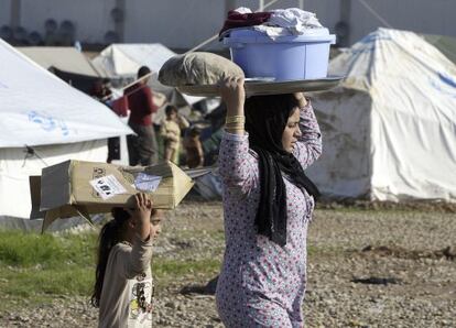 Una mujer yazidí y una niña llevan en el campo de refugiados de Baharka, en Irak