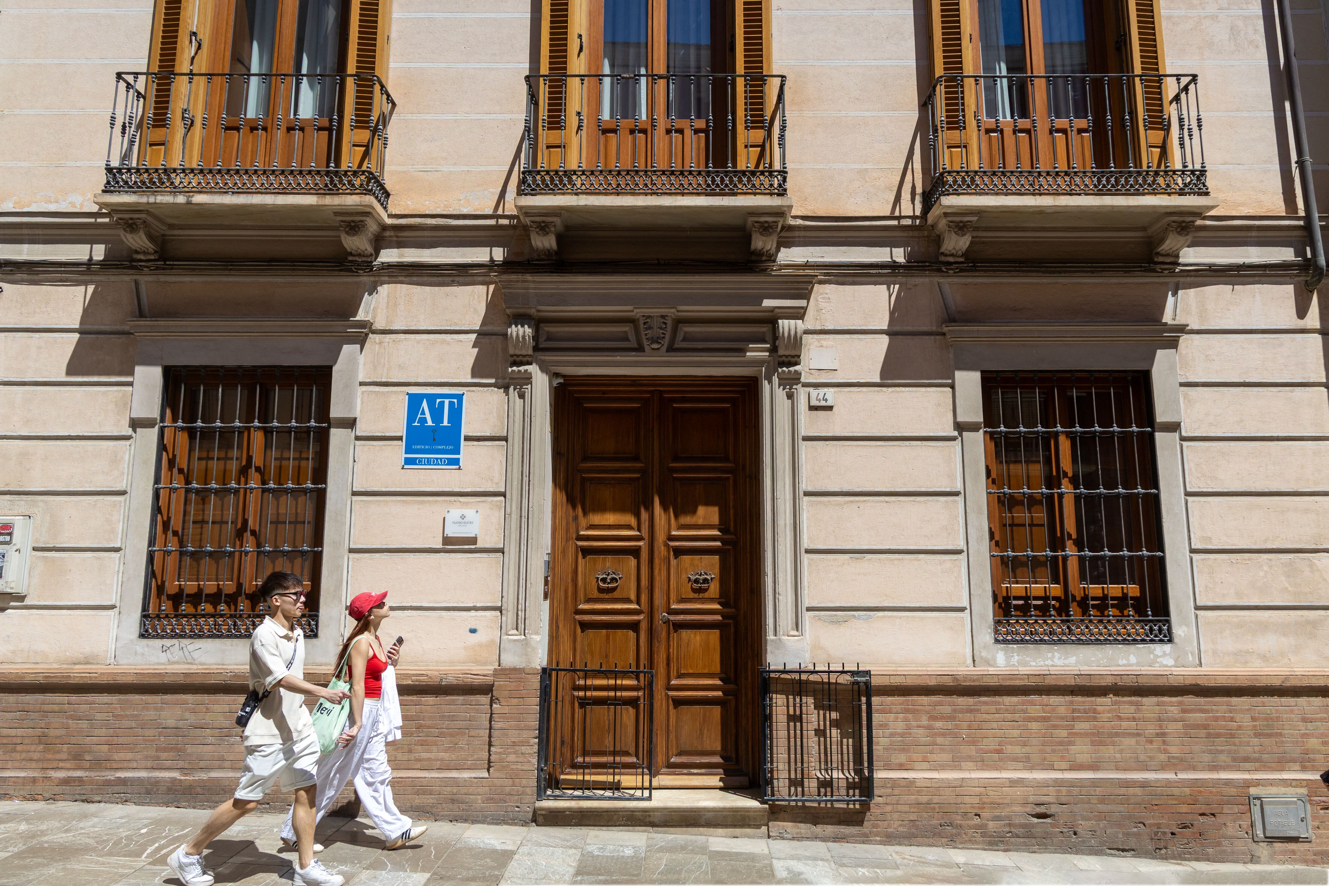 Dos personas pasan por delante de un edificio de apartamentos turísticos, en calle Madre de Dios, en Málaga. 