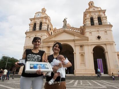 Carina Villarroel y Soledad Ortiz posan con su hija Umma Azul a las afueras de la catedral de C&oacute;rdoba tras el bautizo. 