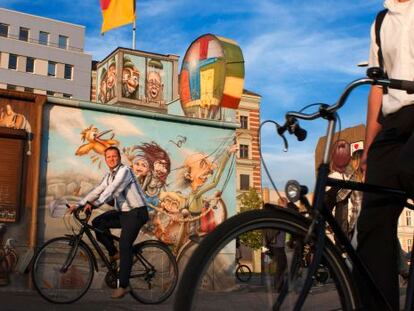 Ciclistas paseando por la East Side Gallery de Berl&iacute;n al atardecer. 