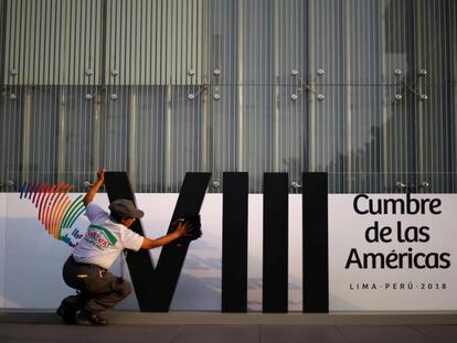 Mulher limpa o logotipo da Cúpula das Américas em Lima