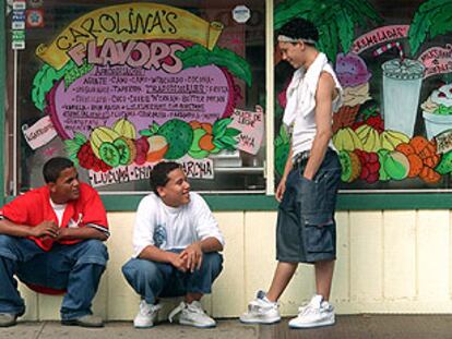 Tres jóvenes, ante el escaparate de un comercio de la calle de Paterson, en Nueva Jersey, que ofrece sus productos en español.