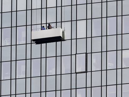 Dos trabajadores limpian los cristales de un edificio, en Frankfurt (Alemania).