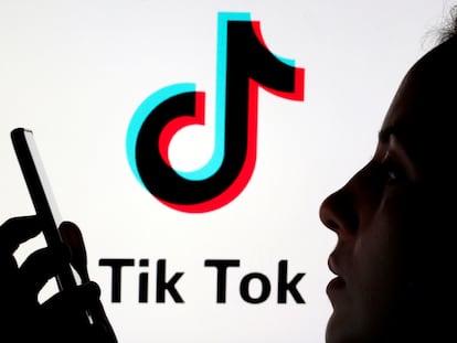 Una persona sostiene un teléfono móvil ante el logotipo de la red social china Tik Tok.