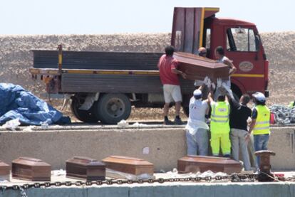 Varios voluntarios cargan los ataúdes con los cuerpos de algunos de los inmigrantes muertos, en el puerto de Lampedusa.