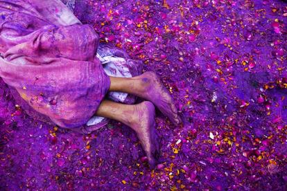 Una mujer descansa en el suelo junto con polvos de colores y pétalos de flores durante la fiesta Holi celebrada en Vrindavan (India), el 3 de marzo de 2015.
