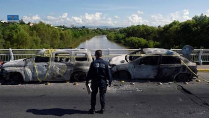 Un policía observa dos coches calcinados durante los ataques en Culiacán.