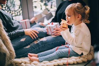 Una pequeña come un bollo, tras recibir los regalos de Navidad.