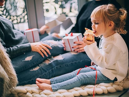 Una pequeña come un bollo, tras recibir los regalos de Navidad.