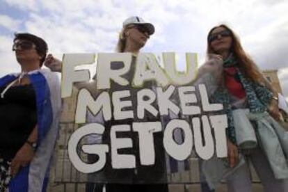 Una manifestante sujeta una pancarta en la que se puede leer "Frau Merkel Lárgate" durante una protesta frente la sede parlamentaria griega, en Atenas, Grecia, hoy.