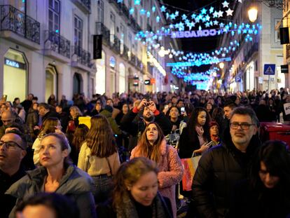 People look up at Christmas lights as crowds stroll around downtown Lisbon's Chiado neighborhood, Saturday evening, Dec. 23, 2023.