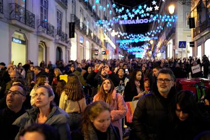 People look up at Christmas lights as crowds stroll around downtown Lisbon's Chiado neighborhood, Saturday evening, Dec. 23, 2023