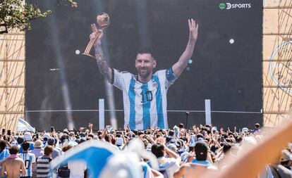 Los argentinos celebran a Messi sosteniendo el Balón de Oro del Mundial a través de una pantalla instalada en Buenos Aires.