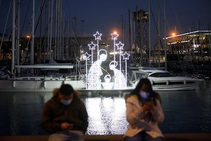 Dos personas junto a un belén luminoso en el puerto de Barcelona, este miércoles.