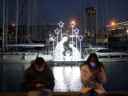 Dos personas junto a un belén luminoso en el puerto de Barcelona, este miércoles.