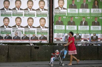 Una mujer pasa con una niña ante carteles electorales en Sarajevo.