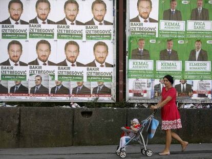 Una mujer pasa con una niña ante carteles electorales en Sarajevo.