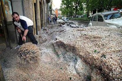 Un hombre recoge con una pala la gran cantidad de granizo que descargó ayer durante la tormenta en Girona.