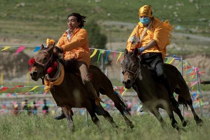 Dos jinetes nómadas tibetanos montan sus caballos en la meseta tibetana, en el condado de Yushú (China).