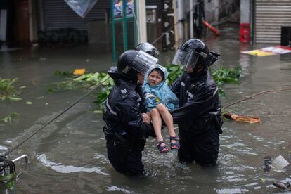 Policías rescatan a un niño de una calle inundada en Lei Yu Mun durante el paso del tifón Mangkhut en Hong Kong (China), el 16 de septiembre.