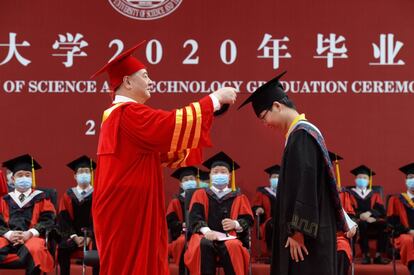 El rector de la Universidad de Ciencia y Tecnología de Huazhong, Li Yuanyuan, le coloca el birrete a un estudiante durante la ceremonia de graduación, en la ciudad china de Wuhan.