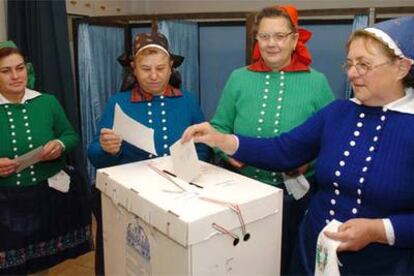 Tres mujeres de un pueblo cercano a Bucarest depositan el voto vestidas con su traje tradicional.