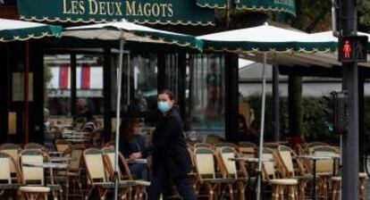 Una mujer pasa por delante del restaurante Les Deux Magots en Paris.