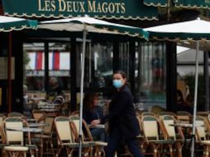 Una mujer pasa por delante del restaurante Les Deux Magots en Paris.