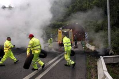 Operarios retiran una de las barricadas de los túneles del Padrún en donde un grupo de mineros cortó el tráfico a las 6,30 de la mañana con barricadas de neumáticos ardiendo en las dos entradas de estos túneles de la A-66 en las próximidades de Oviedo.