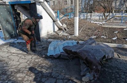Un miembro del servicio de las tropas prorrusas con un uniforme sin insignias se para cerca del cuerpo de una persona que murió durante el conflicto entre Ucrania y Rusia, cerca de un edificio del departamento del ministerio de emergencias en la ciudad controlada por los separatistas de Volnovakha en la región de Donetsk. Ucrania