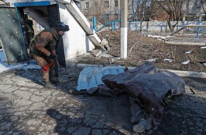 Un miembro del servicio de las tropas prorrusas con un uniforme sin insignias se para cerca del cuerpo de una persona que murió durante el conflicto entre Ucrania y Rusia, cerca de un edificio del departamento del ministerio de emergencias en la ciudad controlada por los separatistas de Volnovakha en la región de Donetsk. Ucrania

