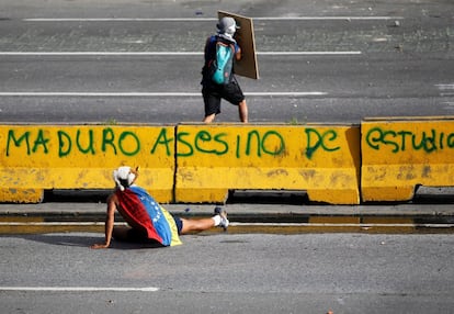Dos manifestantes se protegen durante una protesta en contra de NIcolás Maduro, en Caracas, el 26 de junio de 2017.