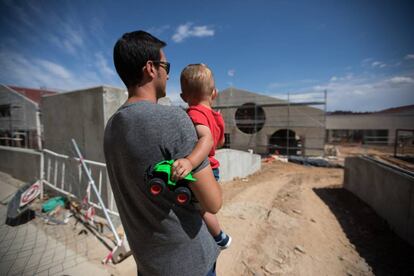 Un hombre con un niño a la hora de salida del cole frente a las instalaciones inacabadas del CEIP Andrea Casamayor en Paracuellos del Jarama.