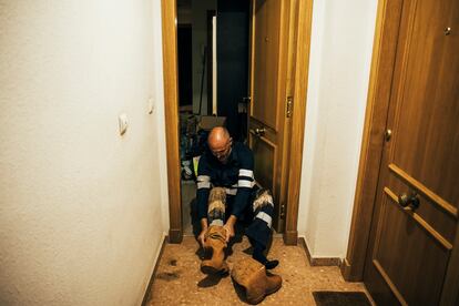 Un vecino de Paiporta se descalza a las puertas de su casa tras estar todo el día quitando barro en la calle. 