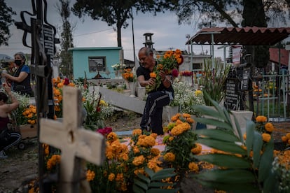 Un hombre adorna la tumba de su familiar. 