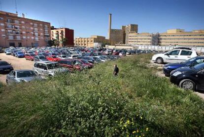 El gran solar del barrio de Tendetes, con los coches aparcados, las hierbas y el hospital La Fe al fondo.