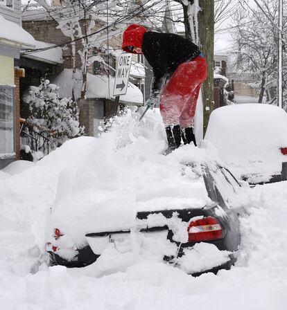 Numerosas zonas de Pensilvania amanecieron el miércoles enterradas bajo más de metro y medio de nieve, que cayó en tan solo 30 horas, un récord para el Estado. En la imagen, una mujer encima de su coche quitándole la nieve en Erie, Pensilvania.