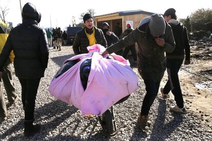 Migrantes trasladan sus pertenencias durante el desalojo.